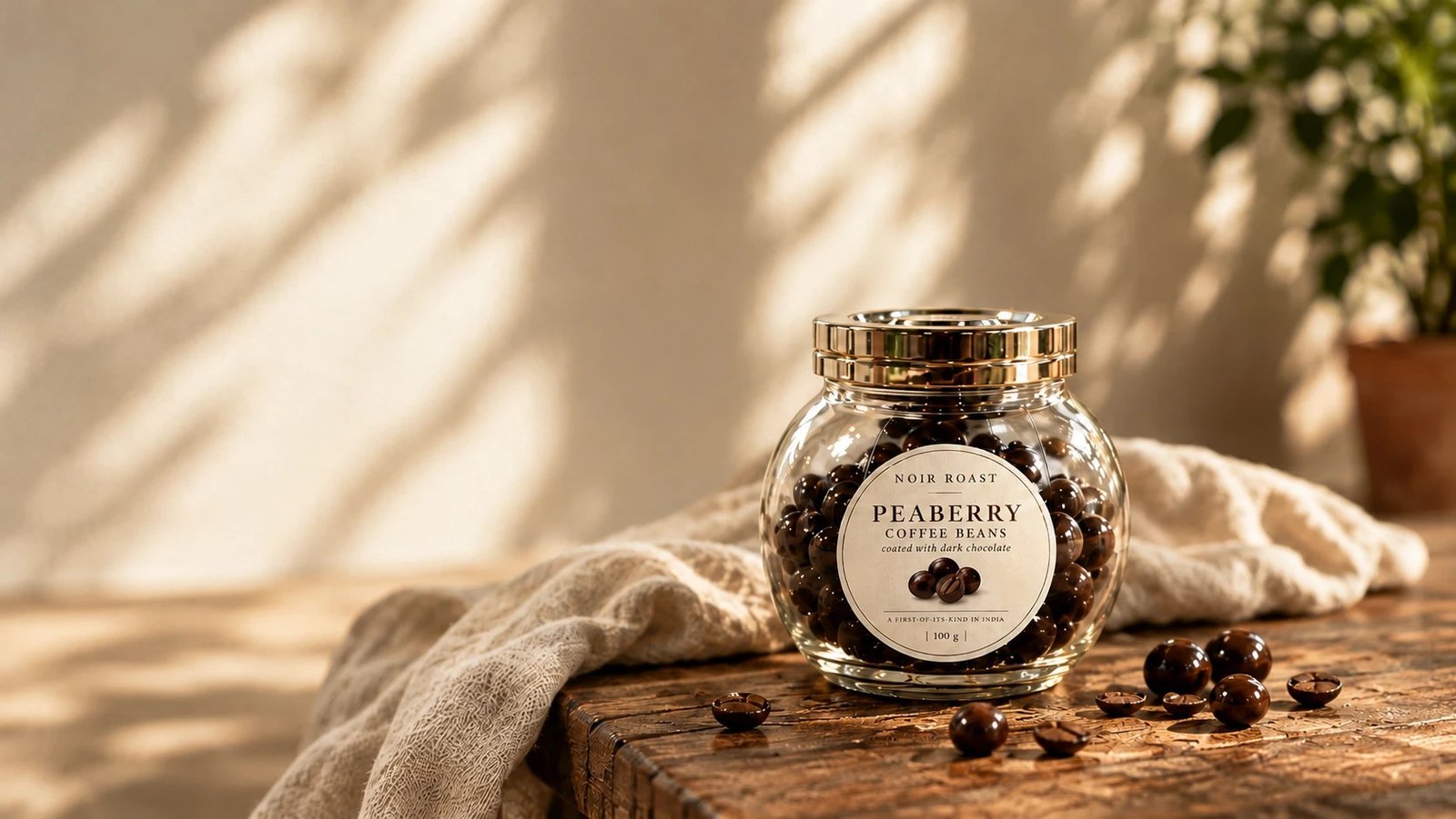 Glass jar of chocolate-coated peaberry beans on a wooden table in warm sunlight